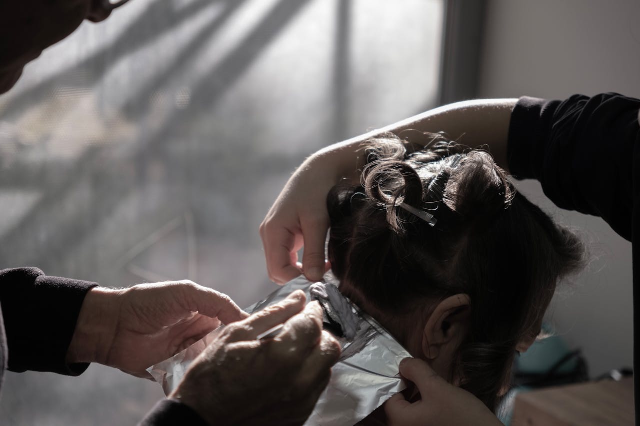 services-03 Expert hairdresser applying color highlights in a salon with natural lighting in İzmir, Türkiye.